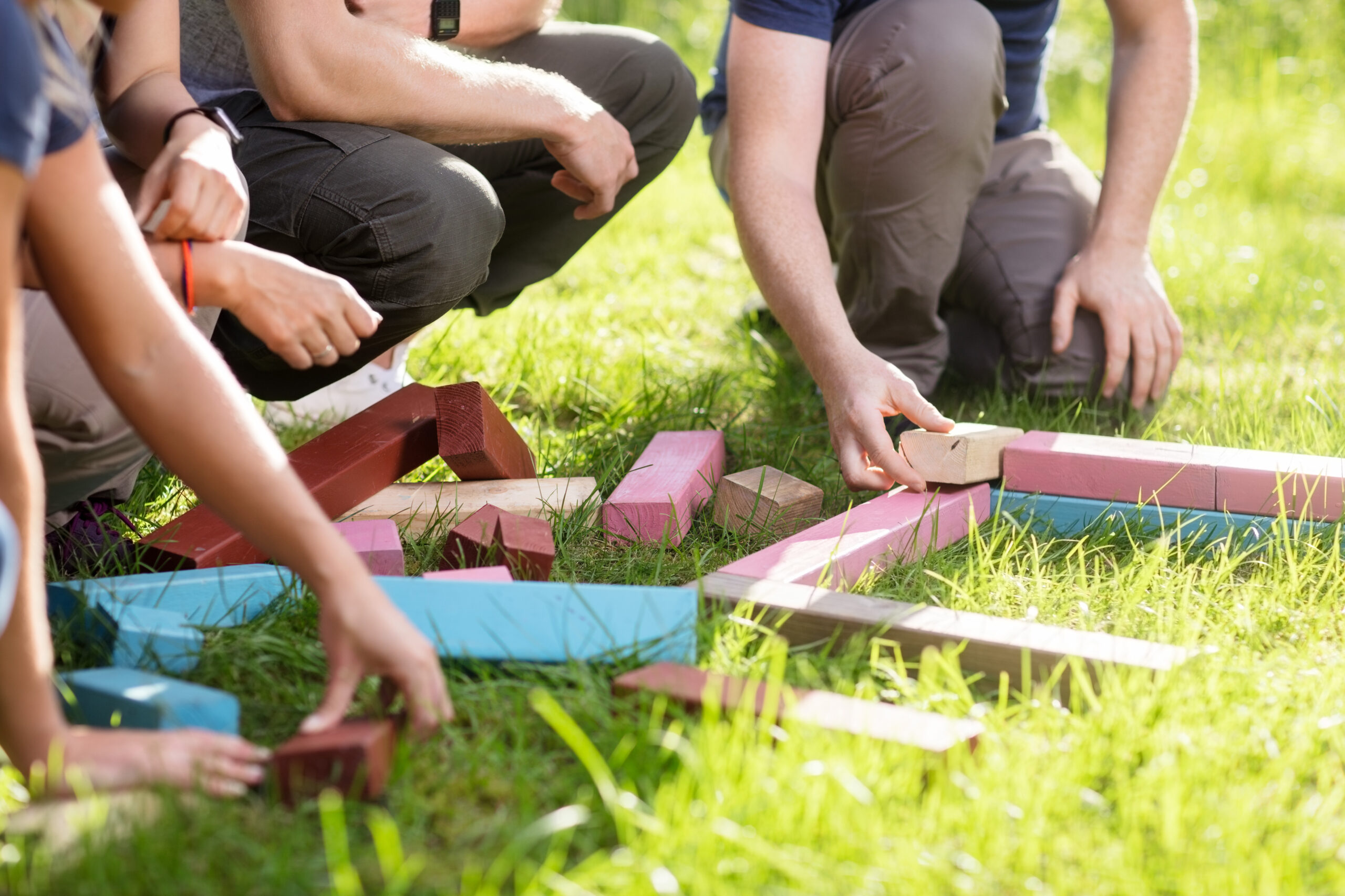 Cropped,Image,Of,Friends,Playing,With,Building,Blocks,On,Field